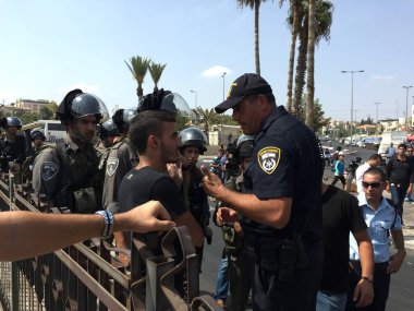 ISRAEL, Kudüs: 2 Ekim 2015 'te İsrail' in Kudüs kentinin dışında bir polis memuru bir adamla konuştu. İnsanların Cuma namazı kılmak için camiye girmesi yasaklandığı için bölge 6 gündür ibadete kapalı..