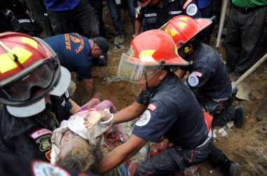 İnsanlar 2 Ekim 2015 'te Guatemala City' nin 15 km doğusundaki Santa Catarina Pinula 'daki El Cambray II köyünde meydana gelen ölümcül çamur kaymasından sonra kurtarabildiklerini kurtarmaya çalışıyorlar.