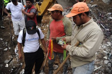 İnsanlar 2 Ekim 2015 'te Guatemala City' nin 15 km doğusundaki Santa Catarina Pinula 'daki El Cambray II köyünde meydana gelen ölümcül çamur kaymasından sonra kurtarabildiklerini kurtarmaya çalışıyorlar.
