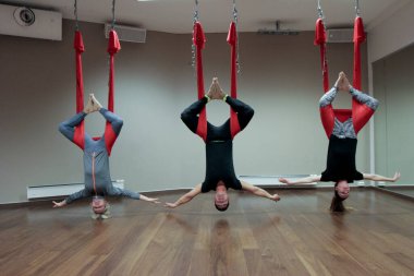 Kadınlar ve erkekler yerçekimi yogası yapıyorlar.