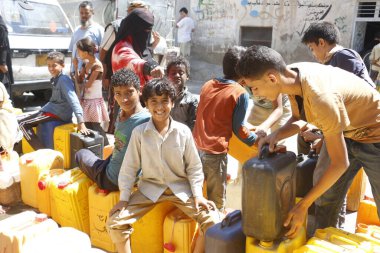 23 Ekim 2015 'te Taiz (Ta' izz), batı Yemen 'deki Nasser okulunda yiyecek ve temiz su dağıtımında içlerini su ile doldurmak için su dolu bidonları taşıyan Yemenli çocuklar görülüyor..