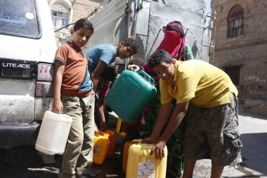 23 Ekim 2015 'te Taiz (Ta' izz), batı Yemen 'deki Nasser okulunda yiyecek ve temiz su dağıtımında içlerini su ile doldurmak için su dolu bidonları taşıyan Yemenli çocuklar görülüyor.