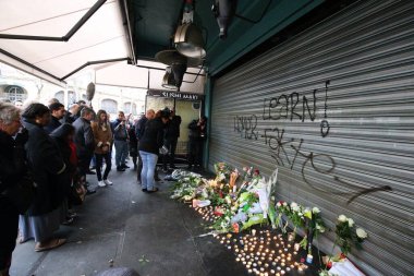 FRANCE, Paris: İnsanlar 14 Kasım 2015 'te Paris' in 11. meydanında Charonne Caddesi 'ndeki' La Belle Equipe 'kafesinin dışına çiçek ve mum koyuyorlar.