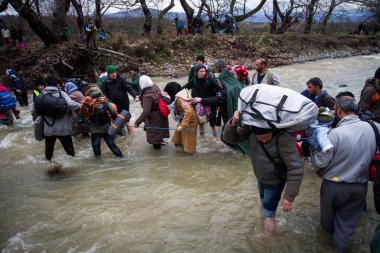 Yunanistan, Idomeni - 14 Mart 2016: Yunanistan 'ın İdomeni köyü yakınlarındaki Yunanistan-Makedonya sınırındaki derme çatma bir kamptan Makedonya' ya giden göçmenler ve mülteciler dalgalı bir nehri geçerek geçiyorlar