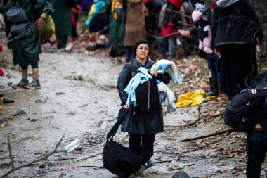 Yunanistan, Idomeni - 14 Mart 2016: Yunanistan 'ın İdomeni köyü yakınlarındaki Yunanistan-Makedonya sınırındaki derme çatma bir kamptan Makedonya' ya giden göçmenler ve mülteciler dalgalı bir nehri geçerek geçiyorlar