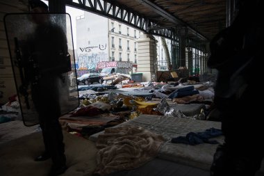 FRANCE, Paris: Polis memurları ve jandarmalar, 30 Mart 2016 'da yüzlerce mültecinin üç hafta süreyle yerleştirildiği Stalingrad tren istasyonunun altındaki geçici bir kamptan göçmen ve mültecileri tahliye ederken nöbet tutuyorlar.