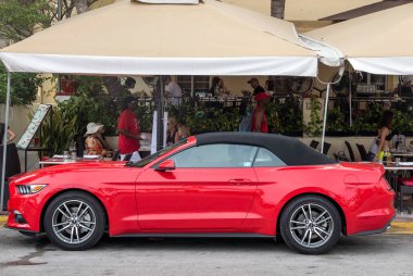 kırmızı Ford Mustang caddeye park etmiş.