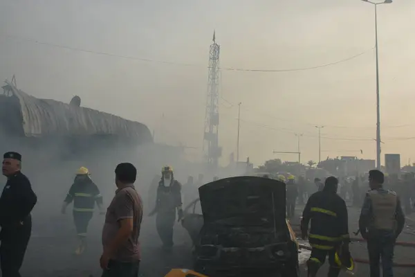 stock image IRAQ, BAGHDAD - APRIL 25, 2016: People gather in a predominantly Shi'ites Muslim district of eastern Baghdad as Iraqi security forces and firefighters secure the site of a suicide bombing claimed by the Islamic State group in New Baghdad area