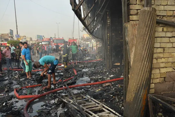 stock image IRAQ, BAGHDAD - APRIL 25, 2016: People gather in a predominantly Shi'ites Muslim district of eastern Baghdad as Iraqi security forces and firefighters secure the site of a suicide bombing claimed by the Islamic State group in New Baghdad area