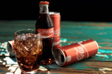 Minsk, Beyaz Rusya-Ağustos 25, 2016. Can ve buzlu Coca-Cola ahşap bir masa üzerinde bir bardak.