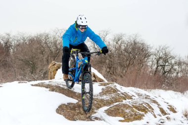 Mavi elbiseli bisikletçi Rocky Winter Hill 'de dağ bisikletiyle dinleniyor. Aşırı spor ve dayanıklı bisiklet konsepti.