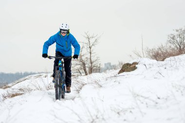 Mavi elbiseli bisikletçi Rocky Winter Hill 'de dağ bisikletiyle dinleniyor. Aşırı spor ve dayanıklı bisiklet konsepti.