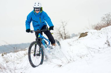 Mavi elbiseli bisikletçi Rocky Winter Hill 'de dağ bisikletiyle dinleniyor. Aşırı spor ve dayanıklı bisiklet konsepti.
