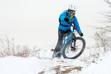 Mavi elbiseli bisikletçi Rocky Winter Hill 'de dağ bisikletiyle dinleniyor. Aşırı spor ve dayanıklı bisiklet konsepti.