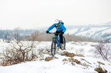 Mavi elbiseli bisikletçi Rocky Winter Hill 'de dağ bisikletiyle dinleniyor. Aşırı spor ve dayanıklı bisiklet konsepti.