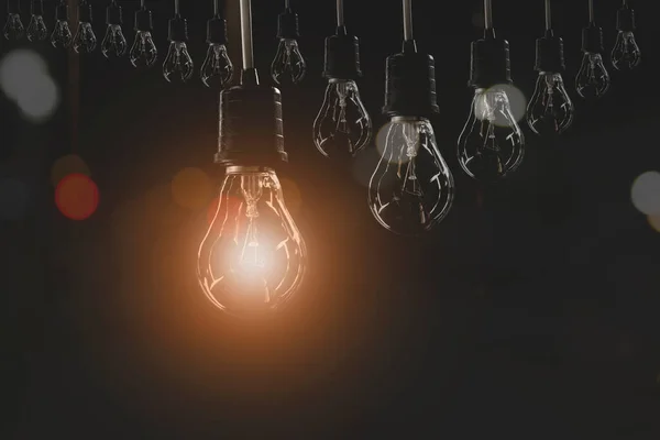 Hanging Light Bulbs Glowing One Dark Background — Stock Photo, Image