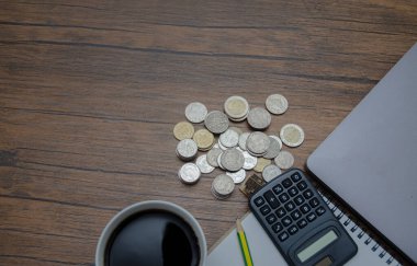 Bozuk paralar ve hesap makinesiyle ahşap masanın yakın çekim görüntüsü