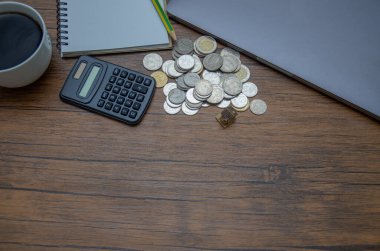 Bozuk paralar ve hesap makinesiyle ahşap masanın yakın çekim görüntüsü
