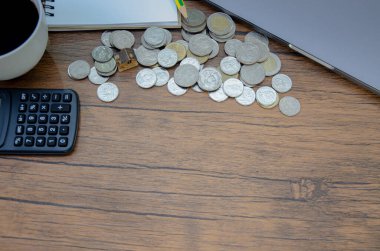 Bozuk paralar ve hesap makinesiyle ahşap masanın yakın çekim görüntüsü