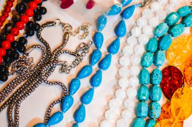 Temel metallerden yapılmış mücevherler ve beyaz zemin üzerinde yarı değerli taşlar.