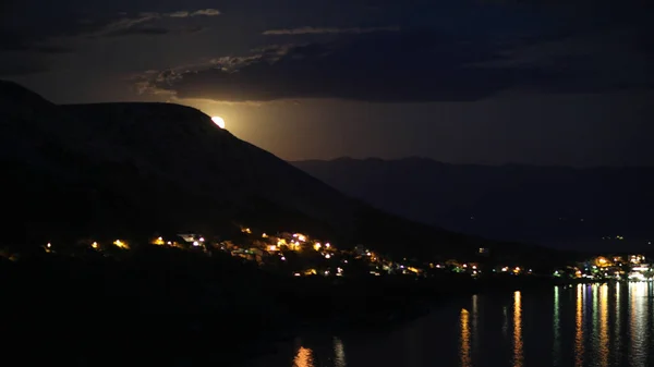 クロアチアの岩場の丘からアドリア海沿岸の都市への月の光の下での夜景 異なる色の色調 — ストック写真