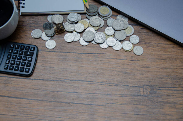 Close-up shot of wooden desk with coins and calculator
