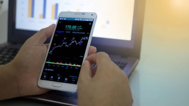 Akıllı telefon ve dizüstü bilgisayarla çalışan iş adamı, hisse senedi alım-satımı konsepti 