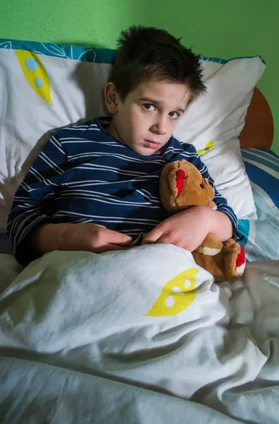 Sick child in bed with teddy bear