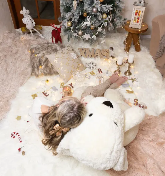 一个女人坐在圣诞树前的地毯上 — 图库照片
