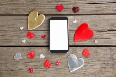 Kalp şeklindeki dekorasyonla çevrili cep telefonu.