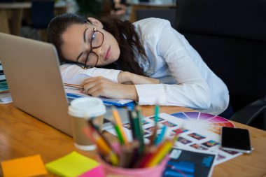 Yorgun kadın grafik tasarımcı masa başında uyuyor