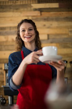 Gülümseyen garson tezgahta kahve servisi yapıyor.