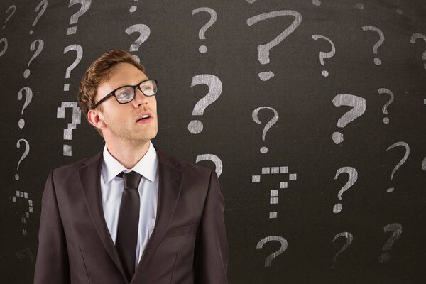 Бизнесмен стоит перед вопросительными знаками