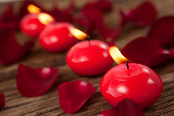 バラの花びらに囲まれた赤いワックスの蝋燭 — ストック写真