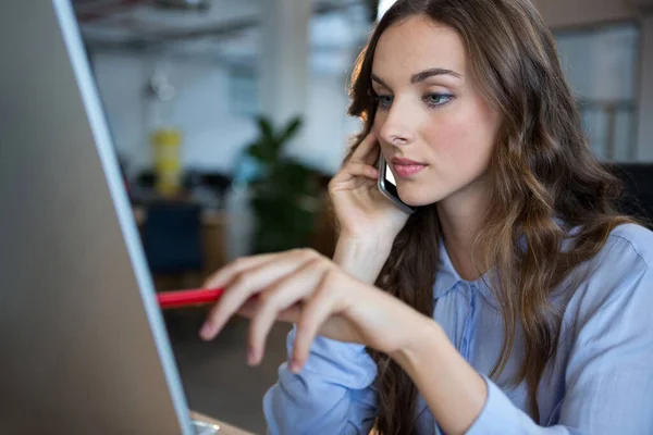 Kadını Masada Cep Telefonu Konuşurken Bilgisayar Üzerinde Çalışma — Stok fotoğraf