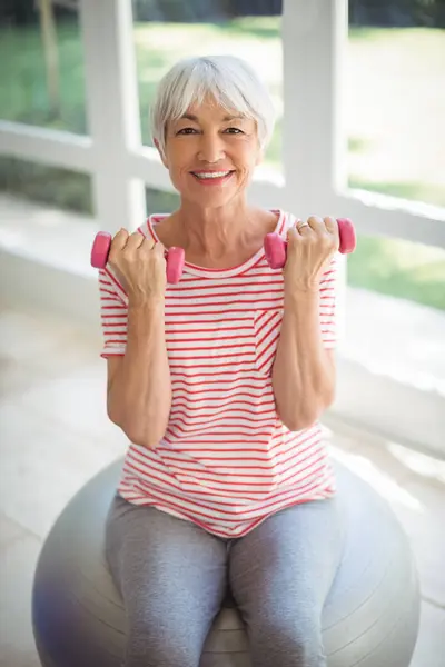 Senior woman exercising with dumbbells\' at home