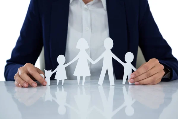 Businesswoman holding paper cut out of family