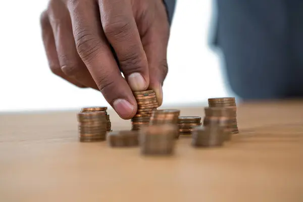 テーブルにコインのスタックを保持するビジネスマン — ストック写真