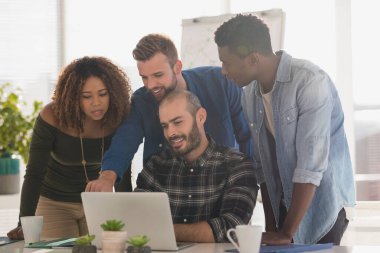 Yöneticilerden oluşan bir ekip bilgisayarı ofiste tartışıyor.