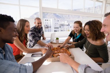 Konferans odasında pizzayı paylaşan mutlu yöneticiler