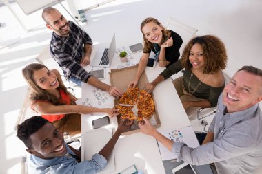 Konferans odasında pizzayı paylaşan mutlu yöneticiler