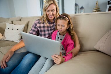 Anne ve kızı salonda dizüstü kullanarak