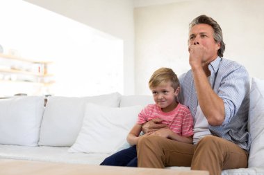 Baba ve oğul oturma odasında tv izliyor