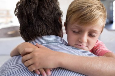 Baba ve oğul birbirlerini oturma odasında kucaklayan