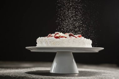 Pudra şekeri beyaz kekin üzerine düşüyor.