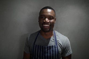 Gri arka planda duran mutlu garson portresi