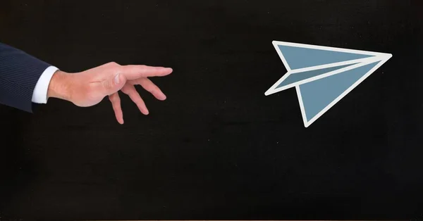 Hand throwing paper airplane in front of blackboard