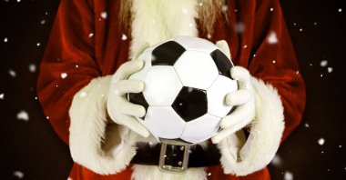 Noel Baba karda bir futbol topu tutuyor.
