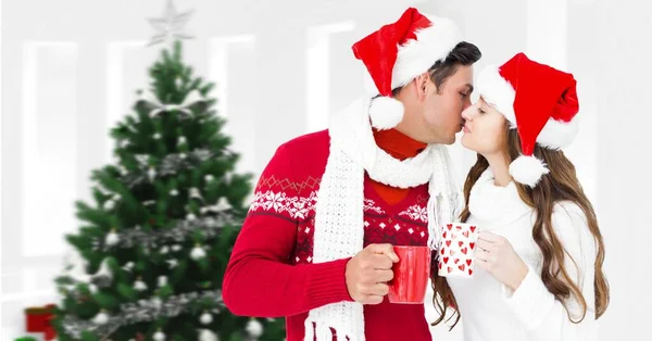 Winter couple drinking cups next to Christmas tree
