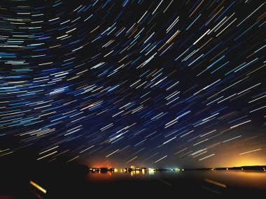 Tver Oblastı 'nın Ostashkovsky Bölgesi' ndeki Seliger Gölü üzerinde muhteşem yıldız izleri var. Yıldızlı gece gökyüzünün uzun pozu. 